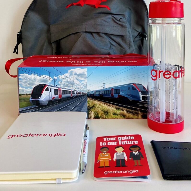 A selection of branded promotional items including a backpack, water bottle, notepad and pen, promotional box and folder leaflet.