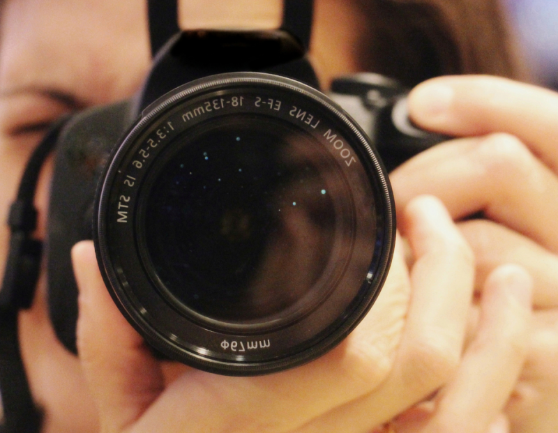 A close up of a woman holding a camera ready to take a photograph.