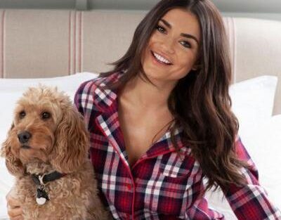 Woman wearing pyjamas sat on a bed with a dog
